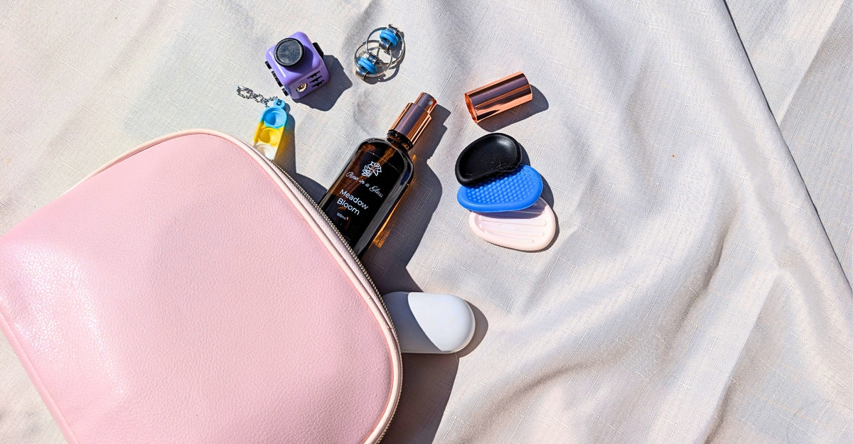 A DIY ON-THE-GO Sensory Kit including a Aromatherapy rommspray from Rose in a Glass, sensory/fidget toys, and a white earbud case.