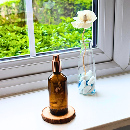 Meadow Bloom Aromatherapy room spray on a windowsill with a rose for a tranquil home environment