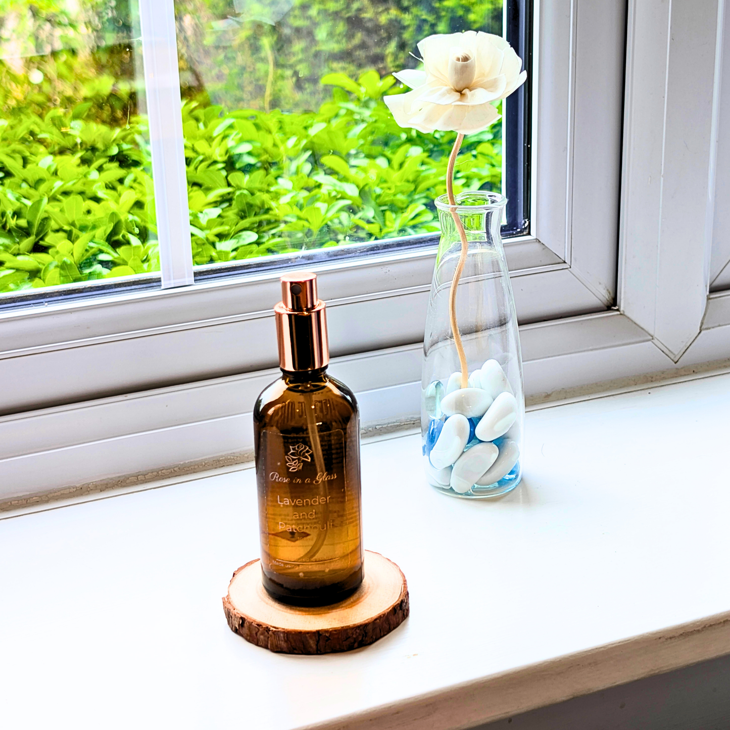 Lavender and Patchouli Aromatherapy room spray on a windowsill with a rose diffuser for a tranquil home environment