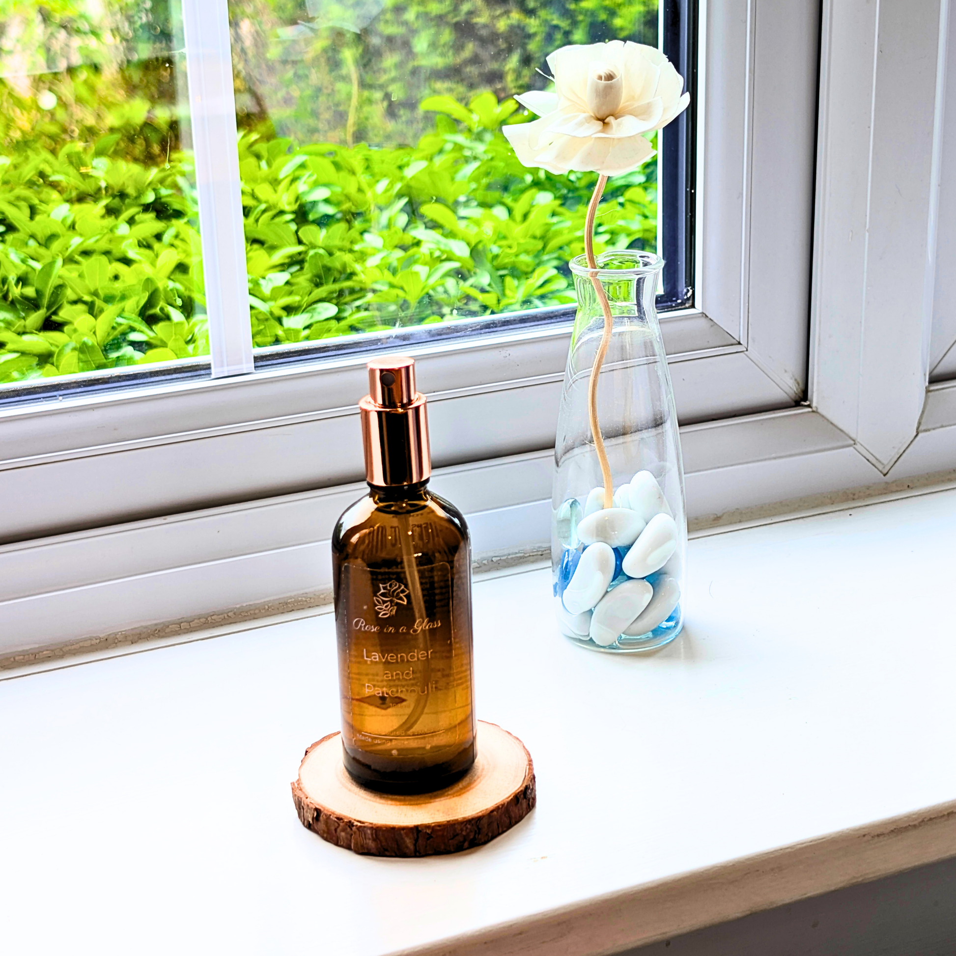Lavender and Patchouli Aromatherapy room spray on a windowsill with a rose diffuser for a tranquil home environment