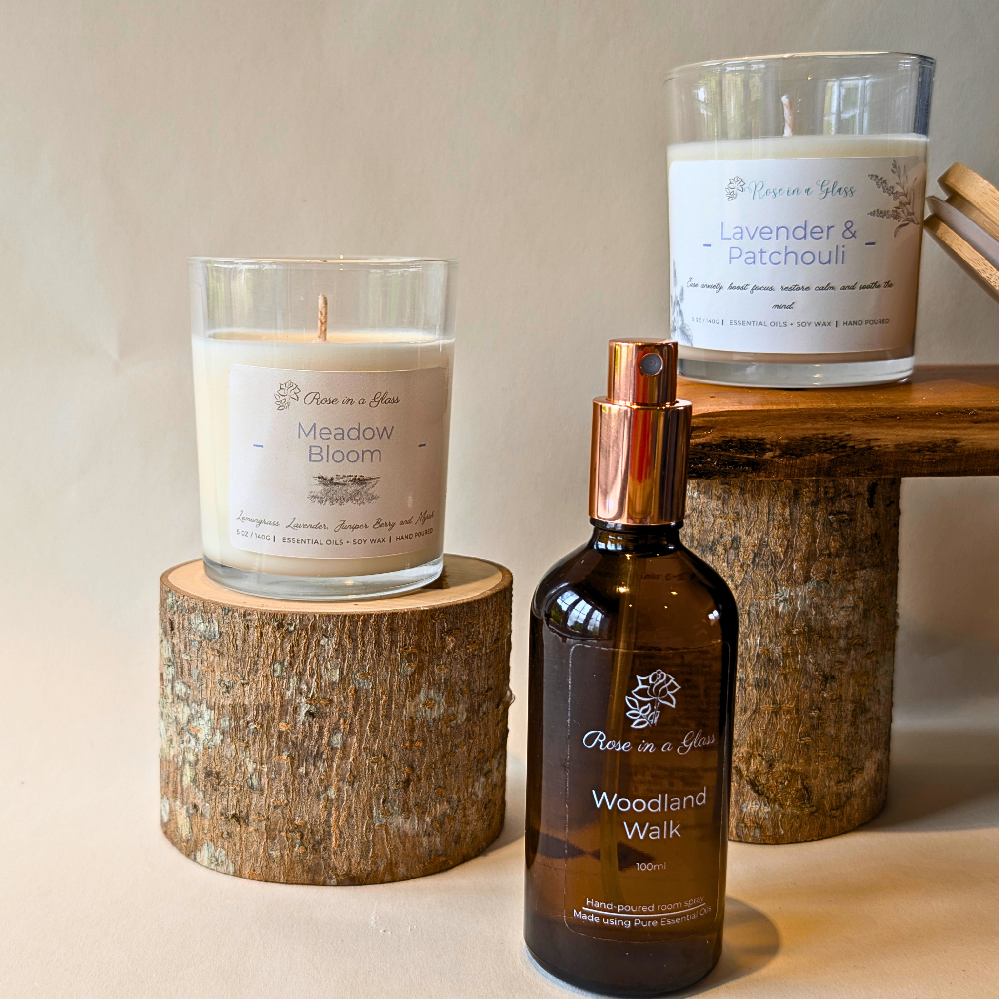 Two candles and a bottle of 'Woodland Walk' on a wooden surface with a neutral background designed to soothe busy minds