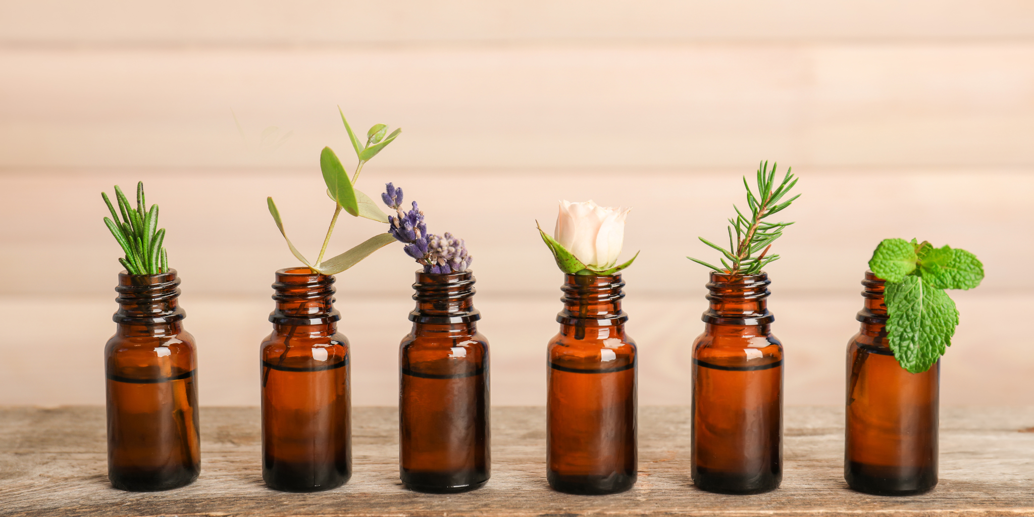 Row of amber glass bottles with plant materials on a wooden surface